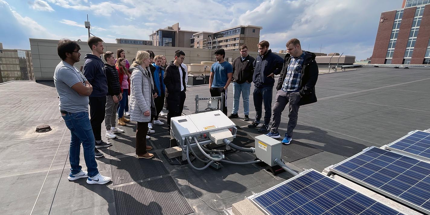 Students on the roof of a building examining solar panels